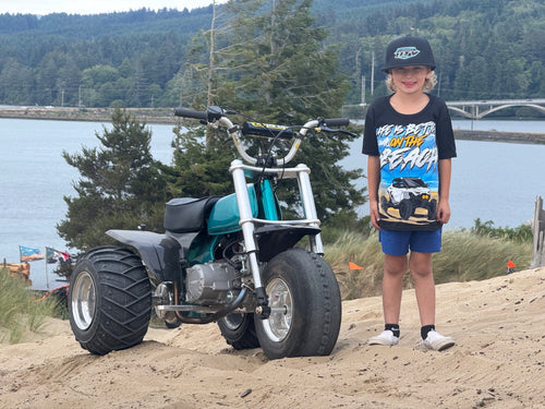 Full view of the Kids Beach Tee worn beside a mini bike overlooking the dunes